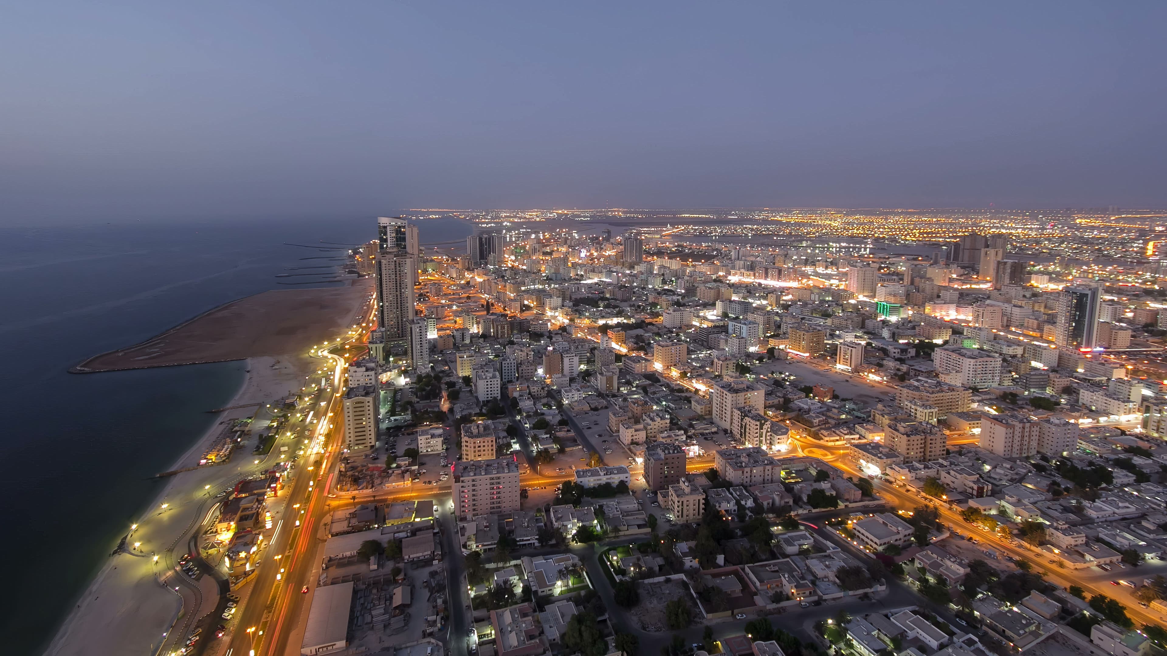 Cityscape of Ajman from rooftop from day to nigh transition aerial timelapse after sunset. 
