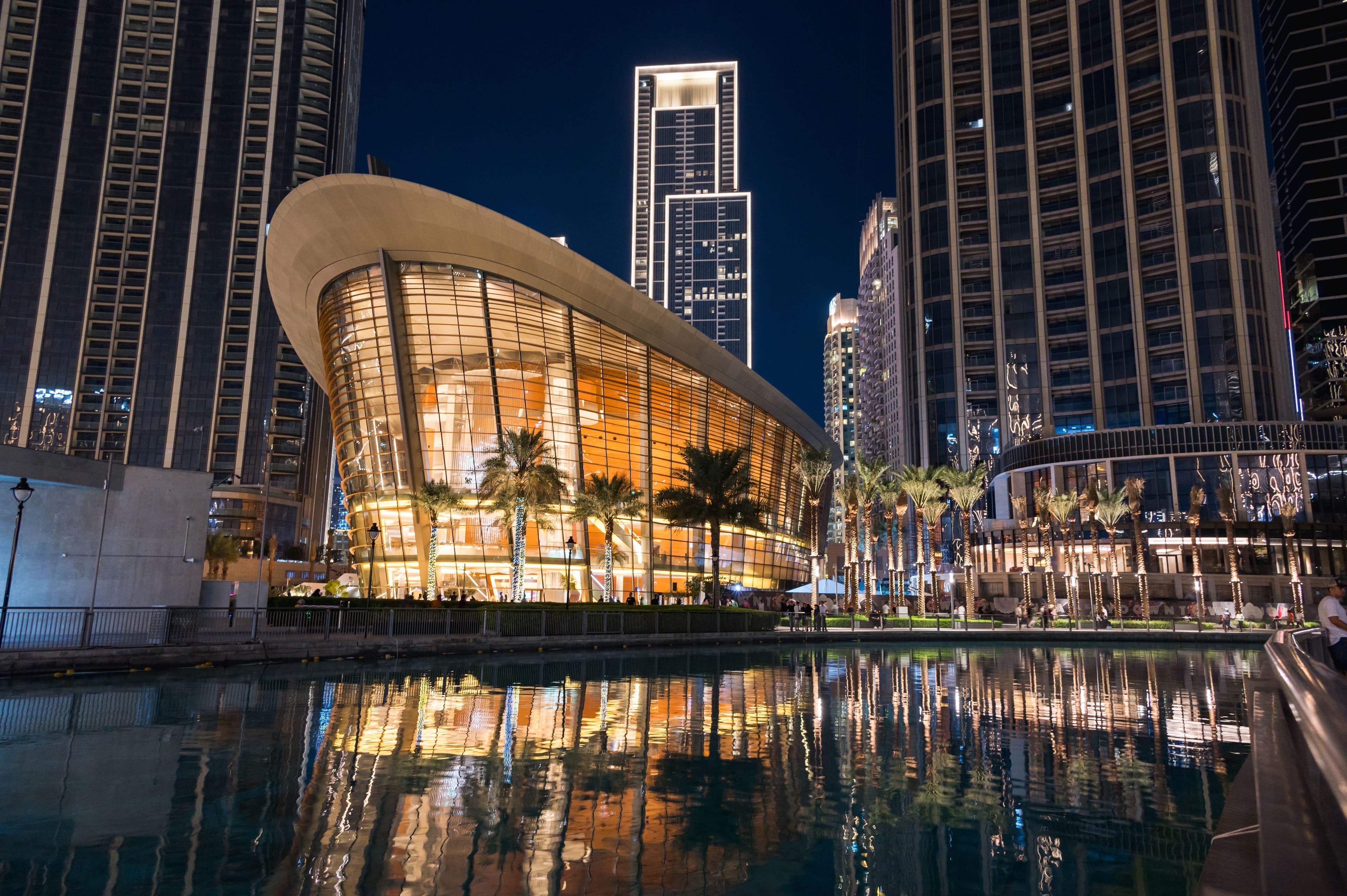 Night view of the Dubai Opera near the Burj Khalifa Tower at night.