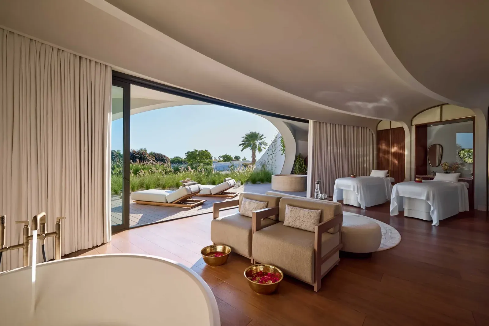 Studio Paolo Ferrari’s interiors highlight organically sculpted details, including monolithic bed platforms, carved oak vanities, and cantilevered mirrors set beneath softly curved ceiling planes.