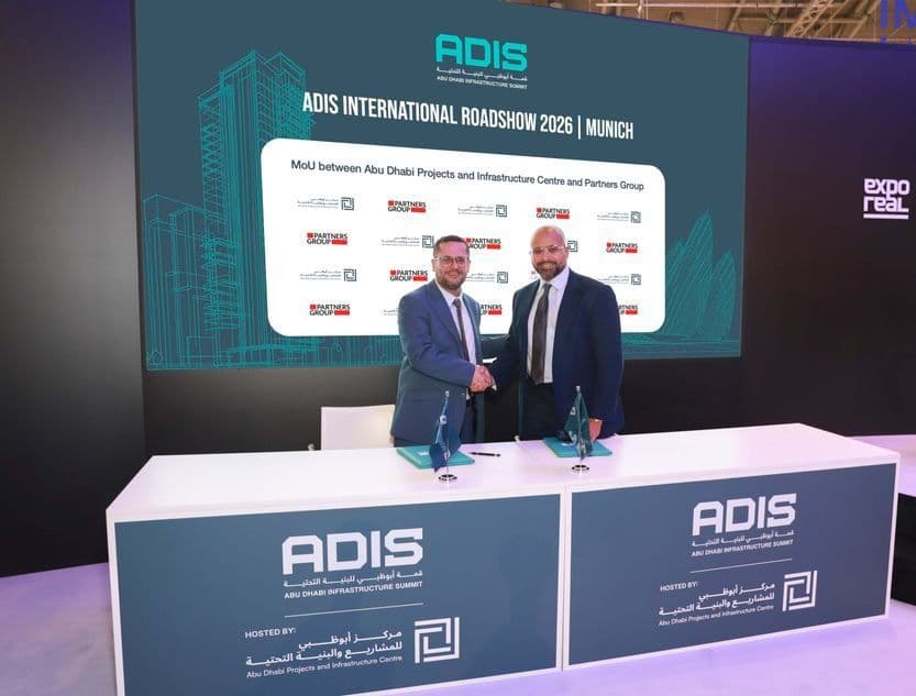 Representatives of ADPIC and Partners Group shake hands after signing their MoU on the ADIS International Roadshow 2026 stand at EXPO REAL in Munich