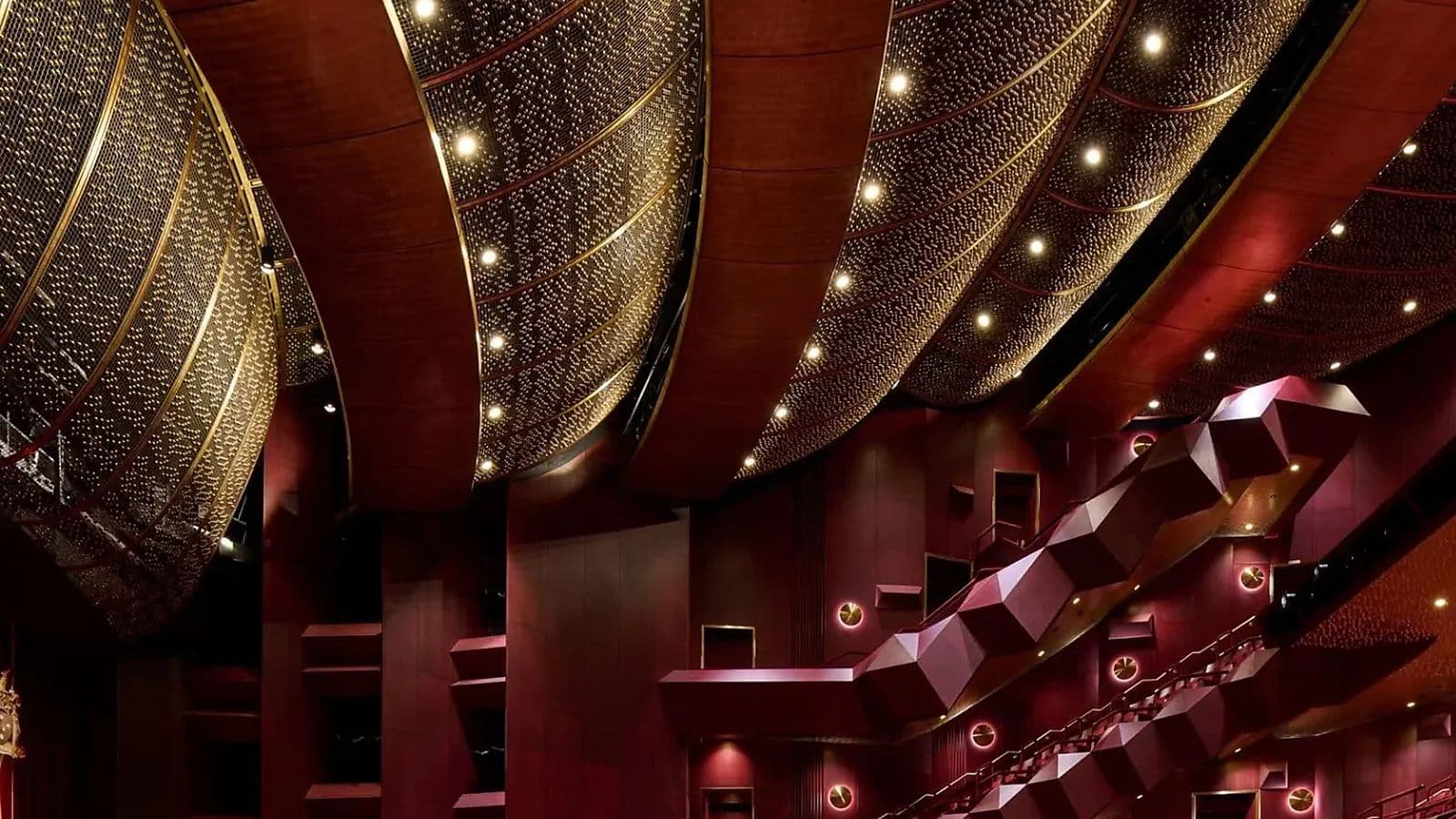 The refurbished auditorium combines curved seating, deep red finishes and the restored brass ceiling that defines the theatre’s interior.