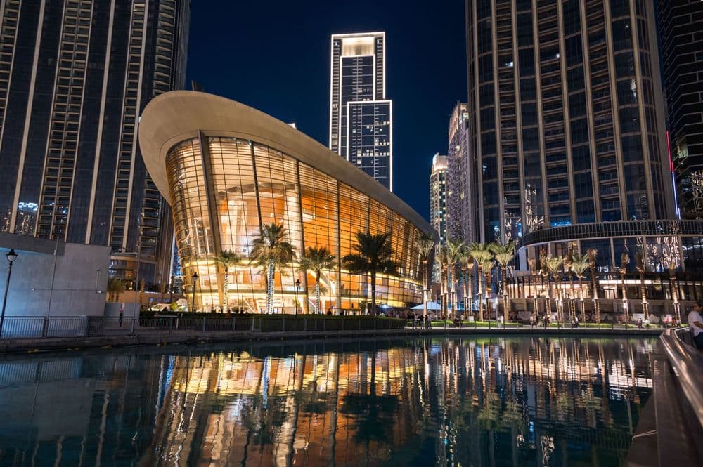 Night view of the Dubai Opera near the Burj Khalifa Tower at night.