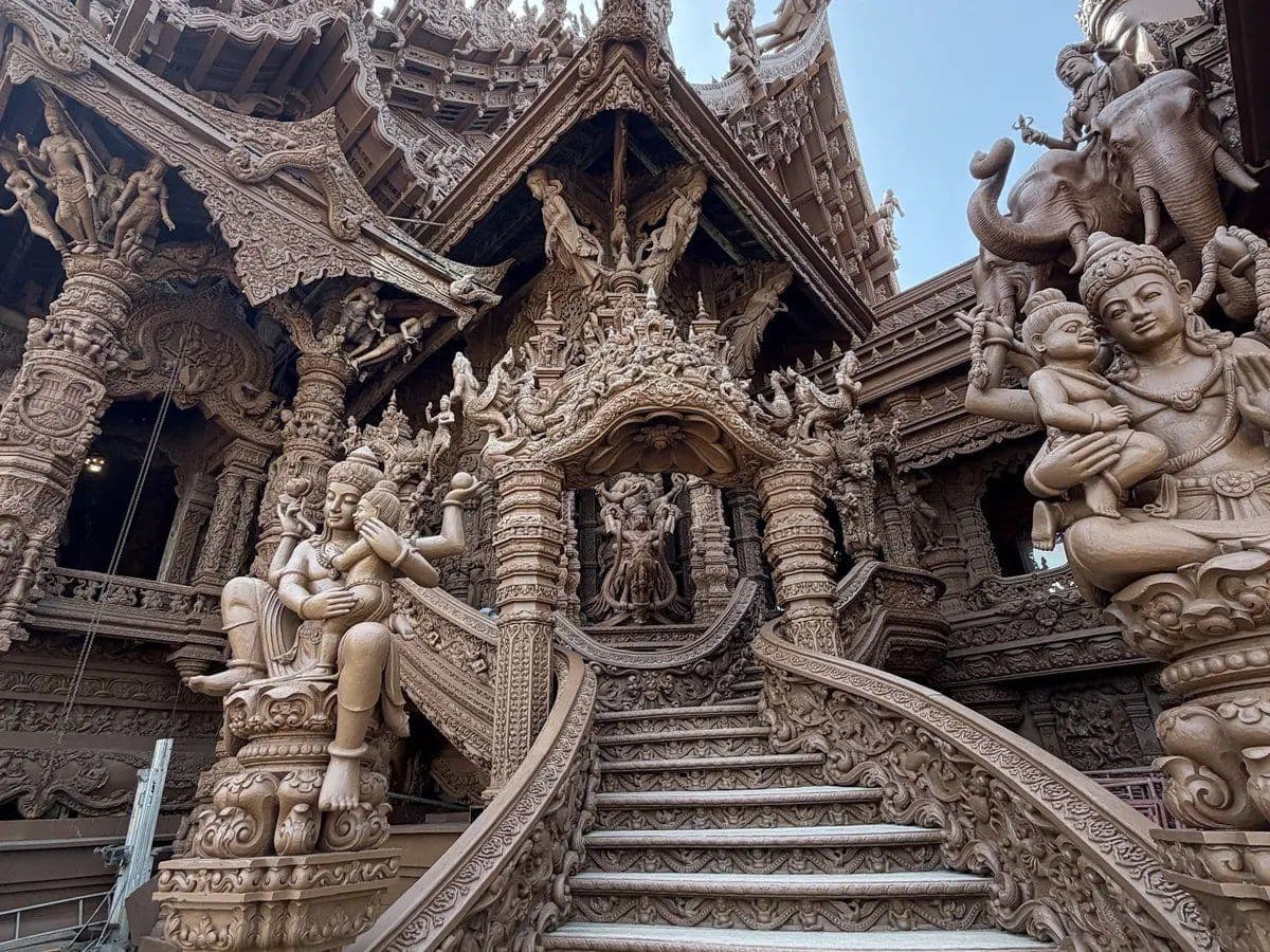 A carved wooden staircase flanked by figures holding children leads into the Sanctuary of Truth