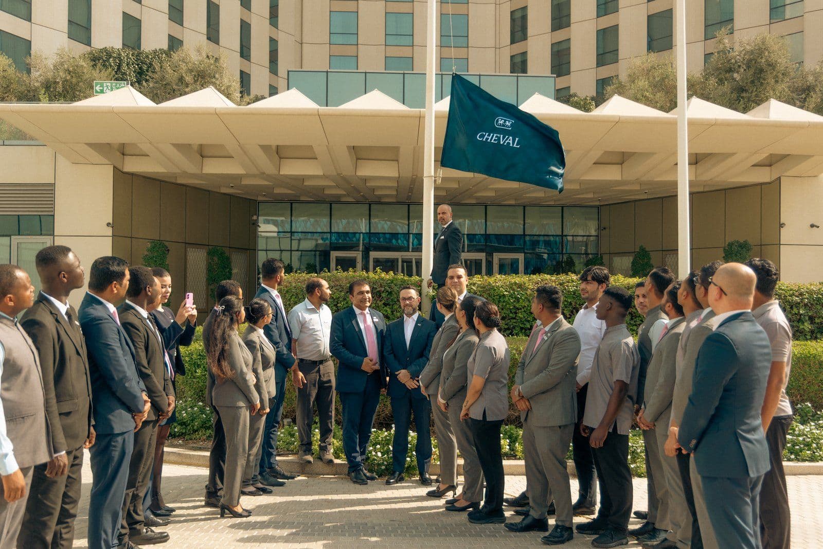 John Raffoul raises a flag bearing the new Cheval logo outside Cheval Maison Expo City Dubai as staff look on